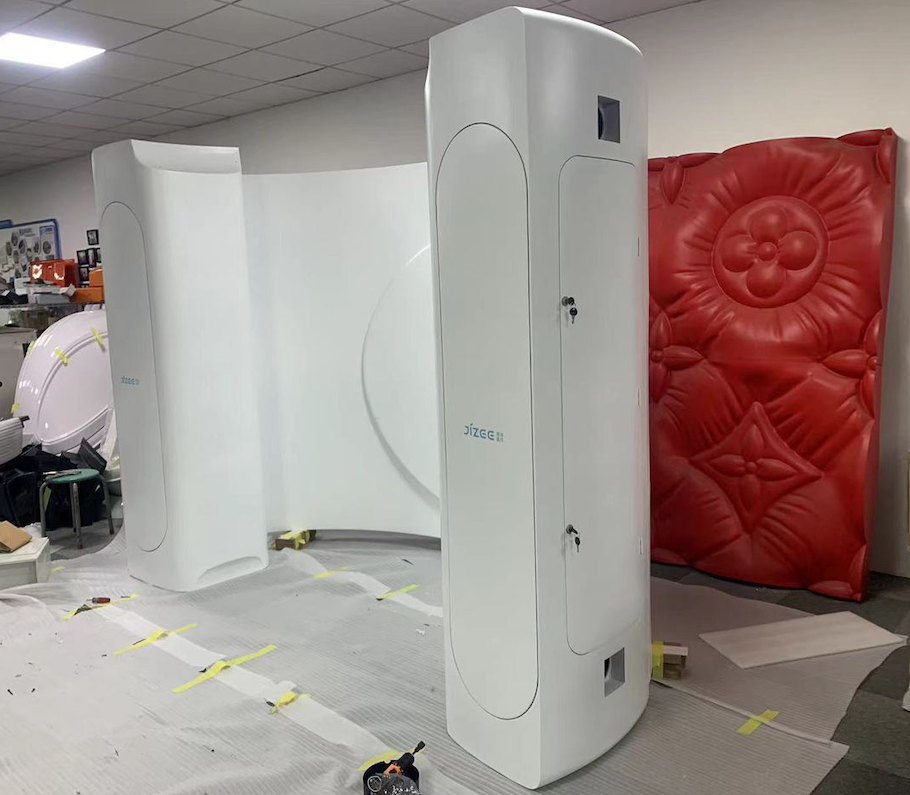 Large upright white enclosure panels and a hinged access section in the workshop